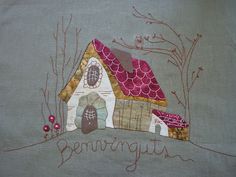 a small house with a red roof is embroidered onto the side of a piece of cloth