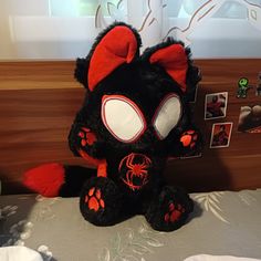 a black and red stuffed animal sitting on top of a bed