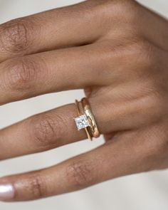 a woman's hand with two gold rings and a diamond ring on her finger