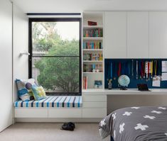 a bedroom with a window seat and bookshelf next to the bed in front of it