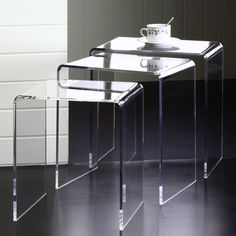 three acrylic tables sitting on top of a black floor next to each other