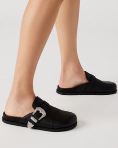 Effortlessly slip into style with our LEDGER mule. The perfect combination of comfort and fashion, these slip-ons make any outfit instantly chic. The western buckle detail adds a touch of edge to any look. 1 inch heel height Leather upper material Synthetic lining Synthetic sock Synthetic sole Imported Trendy Round Toe Mules With Buckle Closure, Trendy Flat Heel Mules With Buckle Closure, Trendy Mules With Buckle Closure And Round Toe, Fall Slip-on Mules With Buckle Closure, Fall Buckle Closure Slip-on Mules, Workwear Fall Buckle Closure Mules, Trendy Clogs With Buckle Closure, Workwear Buckle Closure Fall Mules, Fall Workwear Mules With Buckle Closure