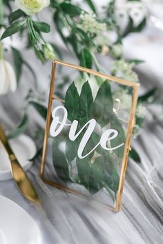 the table is set with white flowers and greenery, including an acrylic sign