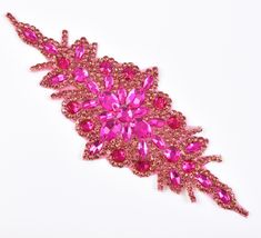 a pink brooch that is on a white surface