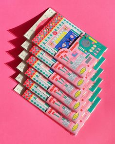 six tubes of toothpaste on a pink background