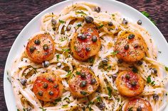 a white plate topped with pasta covered in olives