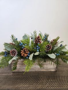 a wooden box filled with pine cones and greenery