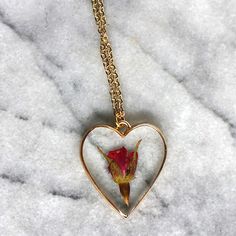 A single rose for the perfect gift for the unique gal in your life. A rose is encased in jewelry grade resin, within an antique bronze or gold plated heart bezel. The bezel is 1 1/2 inches in length and 1 1/4 inches in width- the matching chain is 24 inches. Chain is finished with a lobster clasp. Necklace will arrive attached to card shown in photos. Ready to be gifted! This necklace is custom made. Just like nature, no two will be exactly alike! Let me assure you, though, that we replicate eac Rose Jewelry For Valentine's Day, Rose Heart-shaped Jewelry Gift, Rose-colored Heart-shaped Jewelry For Gifts, Valentine's Day Rose Gold Jewelry With Roses, Rose Heart-shaped Necklace For Gift, Rose Heart-shaped Jewelry For Gift, Valentine's Day Rose Jewelry Gift, Heart-shaped Rose Colored Jewelry For Gift, Valentine's Day Gift Jewelry With Rose Design