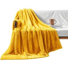 a yellow blanket sitting on top of a bed next to a cup