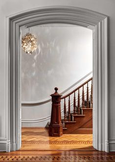 an open door leading to a staircase with a chandelier