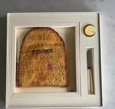 a piece of bread in a white box with a knife and fork next to it