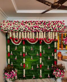 an arrangement of flowers and greenery is displayed on the wall in front of a ceiling fan