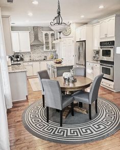 a dining room table and chairs in front of a kitchen with an area rug on the floor