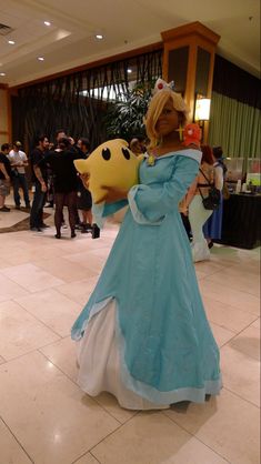 a woman in a blue dress is standing on the floor with a stuffed animal behind her