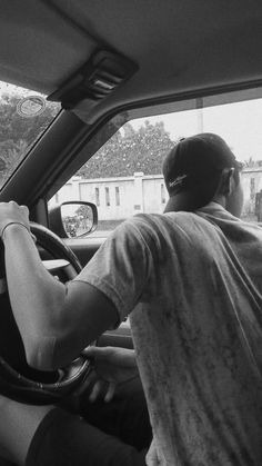 a man sitting in the driver's seat of a car with his hand on the steering wheel