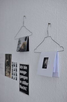 some pictures hang on the wall with clothes pins