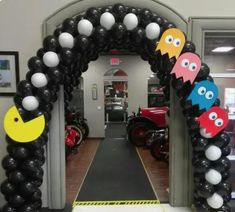 an arch decorated with black and white balloons, pacman faces and ghost heads on it