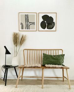 a wooden bench sitting next to two pictures on the wall