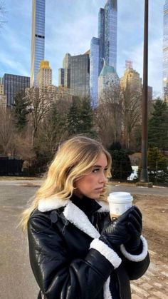 a woman in black jacket holding a coffee cup