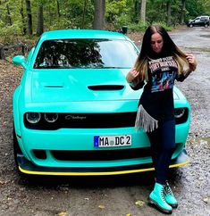 a woman leaning on the hood of a blue car