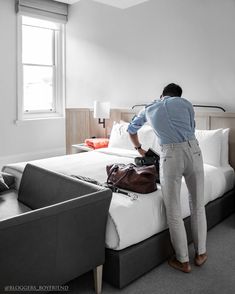 a man standing on top of a bed next to a luggage bag and suitcases