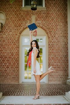 a woman in white dress and red scarf holding up a blue book over her head