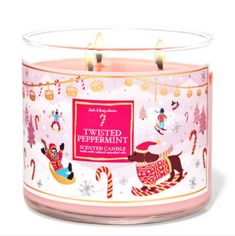 a pink candle that is sitting in front of a white background with christmas decorations on it