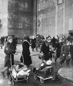 an old black and white photo of people walking down the street with baby strollers