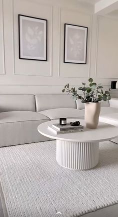 a living room with white furniture and pictures on the wall above it's coffee table