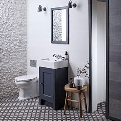 a white toilet sitting next to a sink in a bathroom under a mirror above a wooden stool