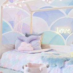 a bedroom with pastel blue and pink decor on the walls, white bedding and pillows