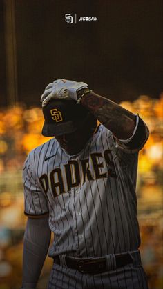 a baseball player is holding his hat over his head and looking to the side with an audience in the background