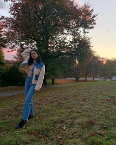 a woman standing on top of a lush green field next to a tree filled with leaves