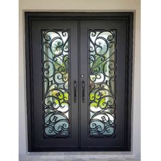 a black double door with glass panels and wrought iron designs on the side walk way