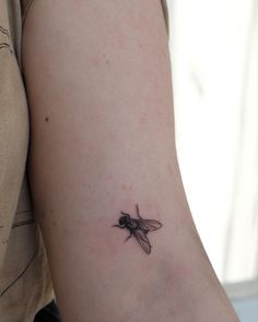 a small black and white insect tattoo on the left side of the right arm,