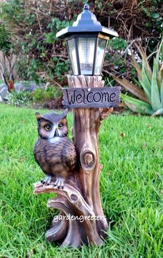 an owl statue sitting on top of a tree stump with a welcome sign attached to it