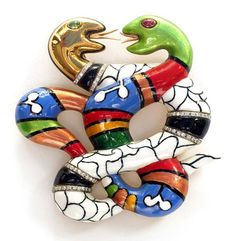 a colorful snake brooch sitting on top of a white surface