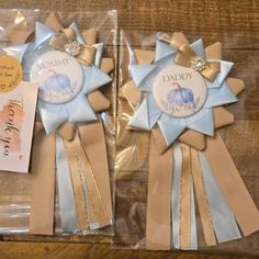 two blue and gold ribbons are on display in plastic bags with tags attached to them