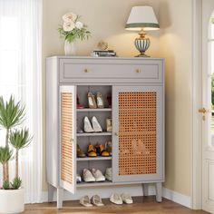 a shoe cabinet with shoes on the bottom shelf and an umbrella lamp next to it