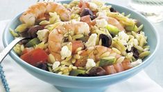 a blue bowl filled with shrimp, olives, and rice next to a fork