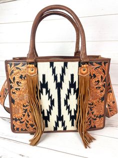 "Wool woven design on leather large tote. Leather tote handles with adorned tassels on front. Detachable tooled leather crossbody strap 48\" long (not adjustable) Zips closed at top Two small open pockets and one zipper pocket inside concealed carry zipper pockets on distressed leather back of bag 16\" wide x 12\" high x 5\" Not customizable - handmade by American Darling Products. Wool pattern may vary slightly" Everyday Rectangular Satchel With Tassels, Rectangular Satchel With Tassels, Leather Satchel With Tassels For Travel, Rectangular Brown Satchel With Tassels, Leather Rectangular Bag With Tassels, Rectangular Leather Bag With Tassels, Hand Tooled Western Bags, Hand Tooled Brown Bag For Rodeo, Western Style Hand Tooled Brown Shoulder Bag