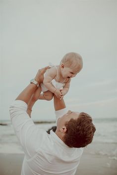 a man holding a baby up in the air