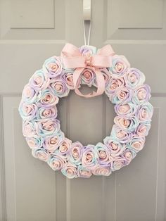 a wreath made out of rolled paper flowers hanging on the front door with a pink bow