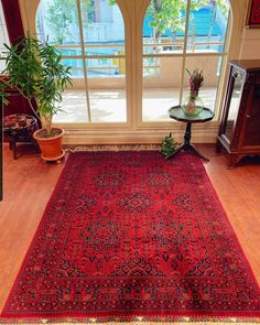 a large red rug sitting on top of a hard wood floor next to a window