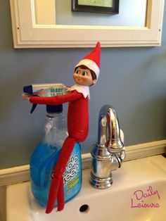 an elf is sitting on top of a blue bottle in the bathroom sink and holding a toothbrush