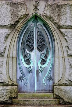 an ornate door is shown in front of a stone wall