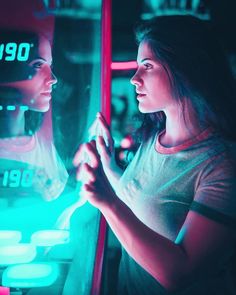 two women standing in front of a neon lit mirror looking into each other's eyes