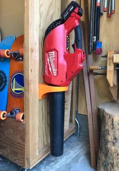 a red and black electric driller in a wooden storage area next to some tools