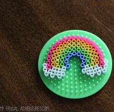 a green plastic plate with a rainbow design on it's side, sitting on a wooden surface