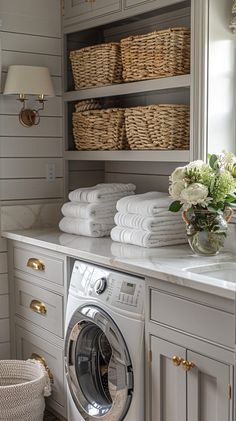 a washer and dryer in a room with lots of towels on the shelves